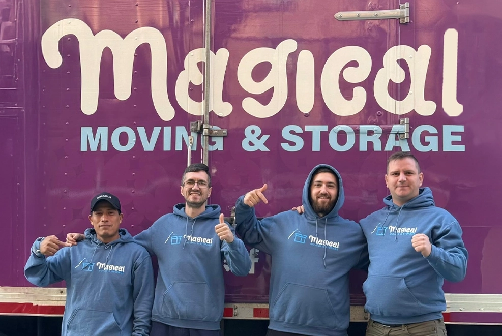 A group of professional movers and packers standing in front of a truck, posing for a camera