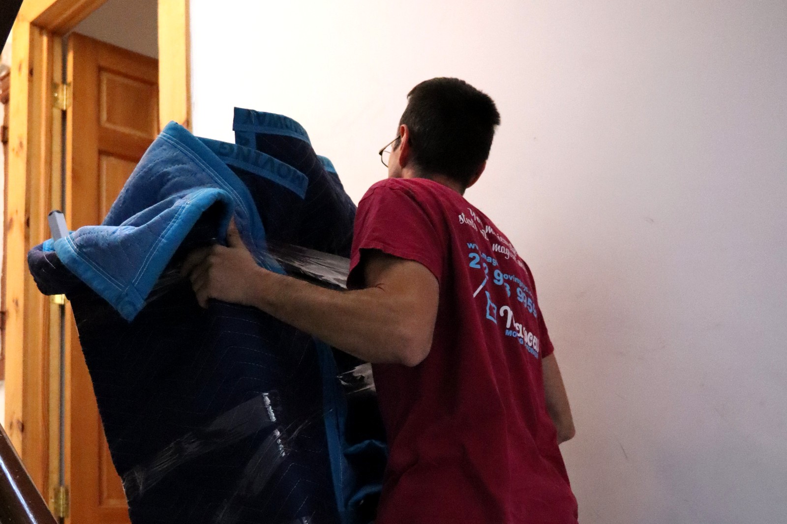 Moving out of a NYC walk-up: Magical Moving crew member carrying wrapped furniture up an apartment staircase
