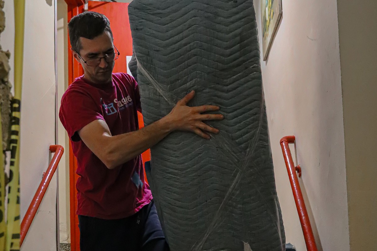 NYC mover carrying a mattress up a narrow stairwell