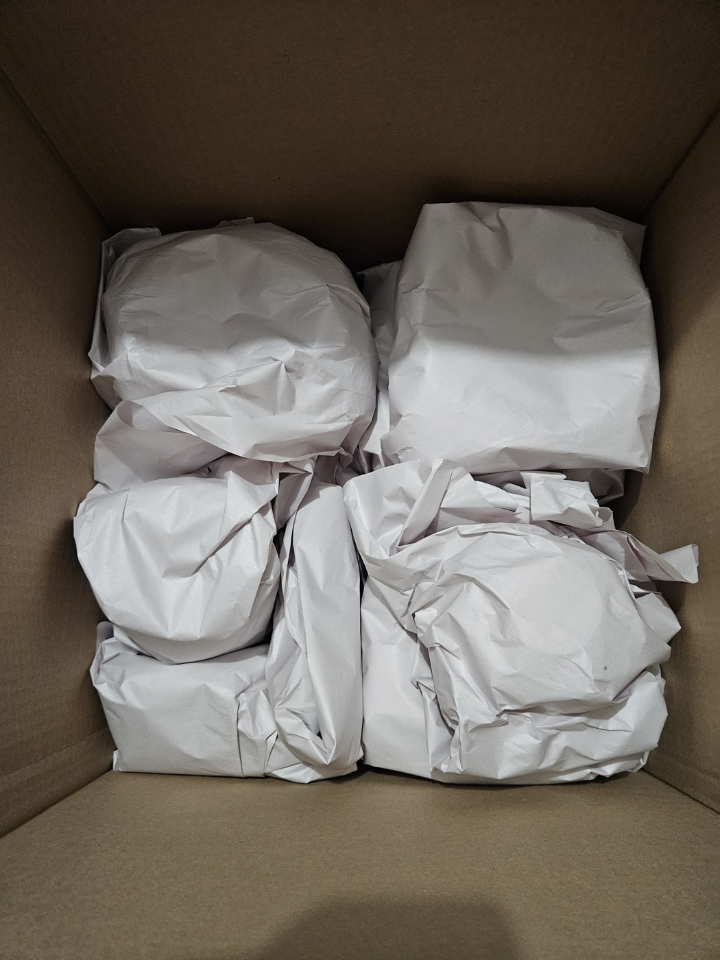 A packed box of paper-wrapped dishes, one line of the inventory to check when you compare moving quotes
