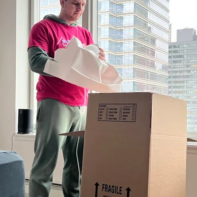A mover packing items into a box with a beautiful view of Manhattan buildings