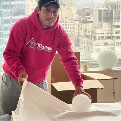 Movers and packers packing round white lamp in Manhattan apartment