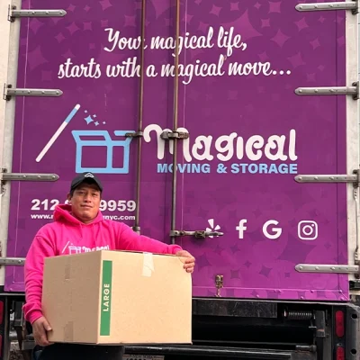 A mover holding on to a large box in front of his moving truck